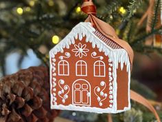 a gingerbread house ornament hanging from a christmas tree