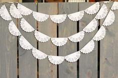 a wooden fence with paper doily hanging from it's sides on top of it