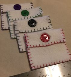 three pieces of fabric with buttons on them sitting next to a measuring tape and ruler