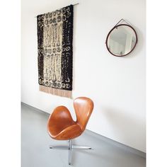 an egg chair sits in front of a wall hanging