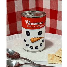 a can of christmas pudding on a plate with crackers and spoons next to it