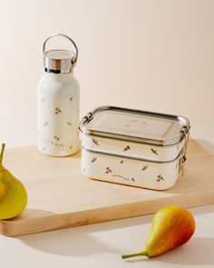 two pears on a cutting board next to a lunch box