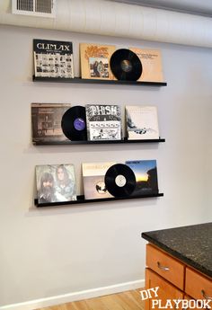 there are three shelves with records on the wall and two vinyls on each shelf