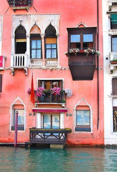 an apartment building with flowers on the windows and balconies above water in venice, italy