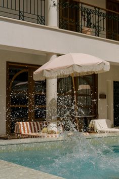 an umbrella is in the middle of a pool with water splashing out of it