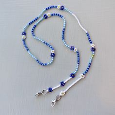 "Keep your mask close with this beaded mask leash that doubles as a cute glasses / sunglasses chain for your continued use post-pandemic.  This is an investment piece that's designed and crafted with high quality craftmanship to stand up to daily use. It only looks delicate!  - Dark blue and light blue iridescent & translucent beads separated with opaque white - Asymmetrical design - Japanese and Czech glass beads - Sterling silver hardware - Double strung on the strongest and most flexible beading thread available for exceptional durability and drape. 24\" length.   Production time is approx 3 days plus shipping. Rush production and rush shipping available as a shipping upgrade at checkout. Stay safe! <3" Blue Beaded Chain Glasses Chains With Round Beads, Blue Beaded Glasses Chains, Blue Glasses Chains With Round Beaded Chain, Trendy Beaded Jewelry For Everyday Use, Trendy Everyday Beaded Jewelry, Blue Adjustable Chain Glasses Chains For Summer, Blue Adjustable Glasses Chain For Summer, Summer Blue Glasses Chain With Adjustable Feature, Blue Beaded Jewelry For Everyday Use