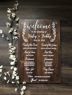 a wooden sign sitting on top of a wooden floor next to a white flower bouquet