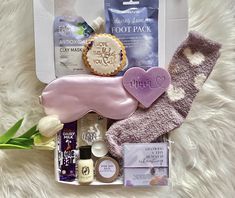 the contents of a women's gift box laid out on a white fur surface