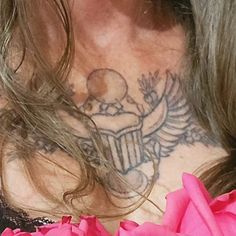 a woman with tattoos on her chest and pink flowers in front of her face is looking at the camera