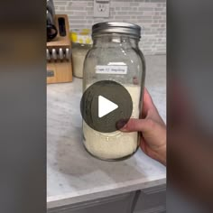 a person is holding a mason jar full of milk and oatmeal in the kitchen