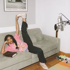 a woman laying on top of a gray couch holding a remote control in her hand