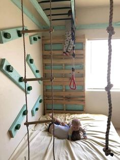 a child laying on top of a bed in a room with wooden ladders hanging from the ceiling