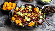 a bowl filled with salad next to bowls of beans and avocado on a table