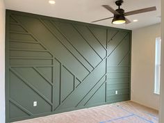 an empty room with green walls and ceiling fan