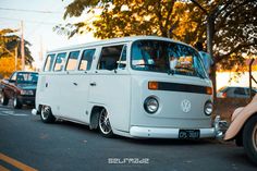 an old vw bus is parked on the side of the road with other cars behind it