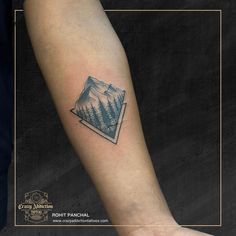 a man's arm with a mountain and forest tattoo on the left inner forearm