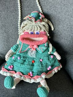 a crocheted doll hanging from a chain on a couch in a living room