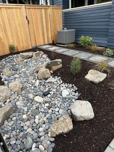 a garden with rocks and gravel in the middle, along side a fenced yard