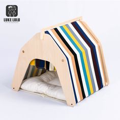 a small wooden dog house made out of strips of wood and white fabric on the inside