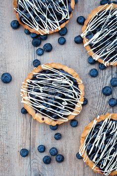 blueberry tarts with white chocolate drizzled on them and fresh blueberries