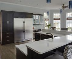 a large kitchen with an island and stainless steel refrigerator freezer combo in the center