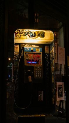 an old fashioned payphone with graffiti on it's sides and lights above the phone