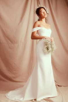 a woman in a white wedding dress holding a bouquet and wearing a tiara on her head