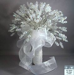 a white vase filled with lots of clear crystal beads and ribbons on top of a table