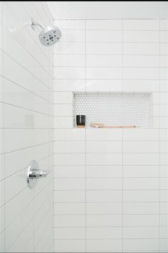 a white tiled shower with a shelf above it