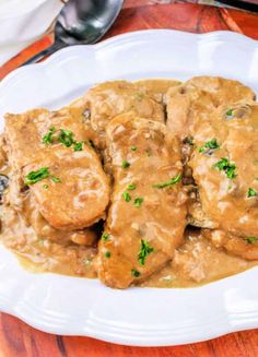 a white plate topped with meat covered in gravy