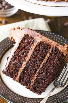 a slice of chocolate cake on a black and white plate with a fork next to it