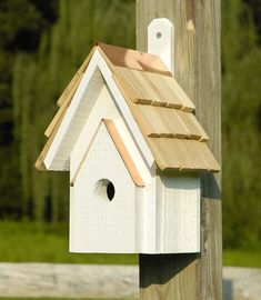 a white bird house on top of a wooden pole