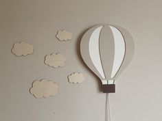 a hot air balloon shaped paper cutout on the wall next to some clouds that are floating in the air