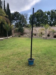 a blue bucket with a black pole sticking out of it in the middle of a yard