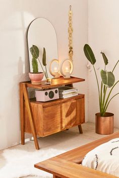 a bedroom with a bed, mirror and potted plants on the side table in front of it