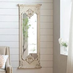 a white mirror sitting on top of a wall next to a chair in a room