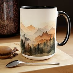 a coffee mug sitting on top of a wooden table next to a spoon and cup