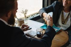 two people sitting at a table shaking hands