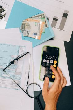 a person is using a calculator on top of papers and other office supplies