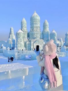 a woman taking a photo of an ice castle