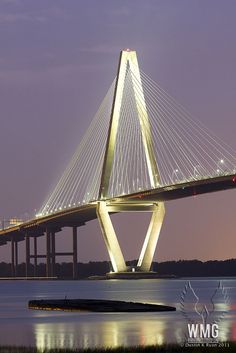 a very tall bridge over some water at night with lights on it's sides