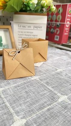 two brown envelopes sitting on top of a table next to a vase with flowers