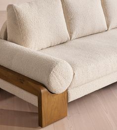 a white couch sitting on top of a hard wood floor next to a wooden frame