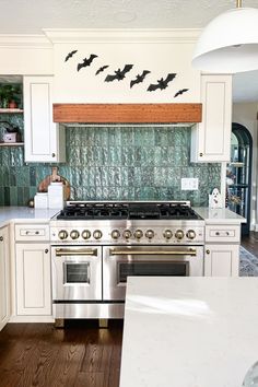 a kitchen with white cabinets and black bats on the backsplash above the stove