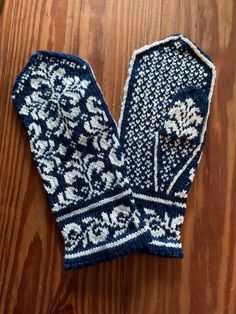 a pair of blue and white knitted mittens on top of a wooden floor