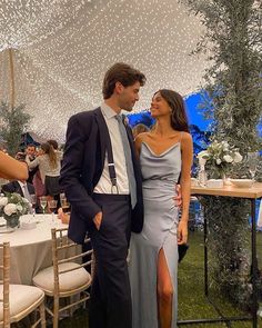 a man and woman standing next to each other in front of a table with white flowers