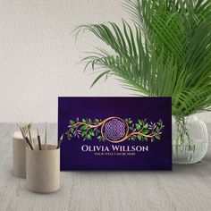 a purple business card sitting on top of a table next to a potted plant