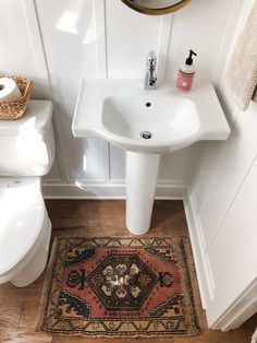 a white sink sitting next to a toilet in a bathroom on top of a wooden floor