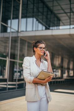 a woman is talking on her cell phone while holding a folder