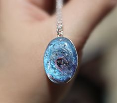 "If you are searching for a truly unique and breathtaking memorial gift, look no further than our milky way pendants! These cremation galaxy necklaces are handcrafted for you with the ashes you provide. Each swirling, shimmery galaxy is set in a 18x25mm oval sterling silver pendant and hangs from your choice of sterling silver chain. These galactic necklaces are built in layers to give them as much depth as possible. In the comments box, please note how defined you would like the \"swirl\" to be Handmade Cosmic Jewelry For Gifts, Handmade Cosmic Style Jewelry For Gifts, Cosmic Style Handmade Jewelry As A Gift, Handmade Silver Cosmic Jewelry, Celestial Style Oval Jewelry Gift, Celestial Style Oval Jewelry For Gifts, Fusion Style Polished Finish Necklaces For Gifts, Celestial Style Necklace With Polished Finish As Gift, Fusion Style Oval Pendant Necklace For Gift